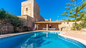 A swimming pool with clear blue water, surrounded by stone buildings and a stone tower. - S'ALQUERIA ROTJA - Magnificent 17th-century estate with a pool in Santanyí (Santanyí)