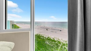 Ett rum med ett stort fönster med utsikt över en strand.