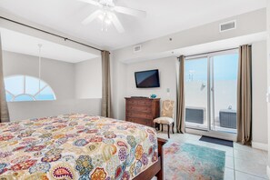 A bedroom with a large bed, a television, a chair, a dresser, and a sliding glass door to a balcony. - Ariel Dunes II 2404 (Miramar Beach)