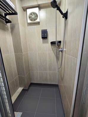 A small, tiled shower room with a handheld showerhead and a wall-mounted fan. - Pillows Co-Living (Kowloon)