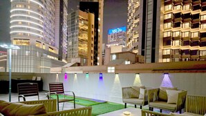 A rooftop lounge with outdoor seating and a view of the city skyline at night. - Pillows Co-Living (Kowloon)