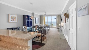 Una habitación de hotel moderna con comedor, un gran ventanal con vistas y un balcón.
