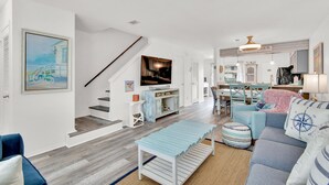 A modern living room with a staircase, a dining area, and a kitchen. - Sandprints A12 (Miramar Beach)