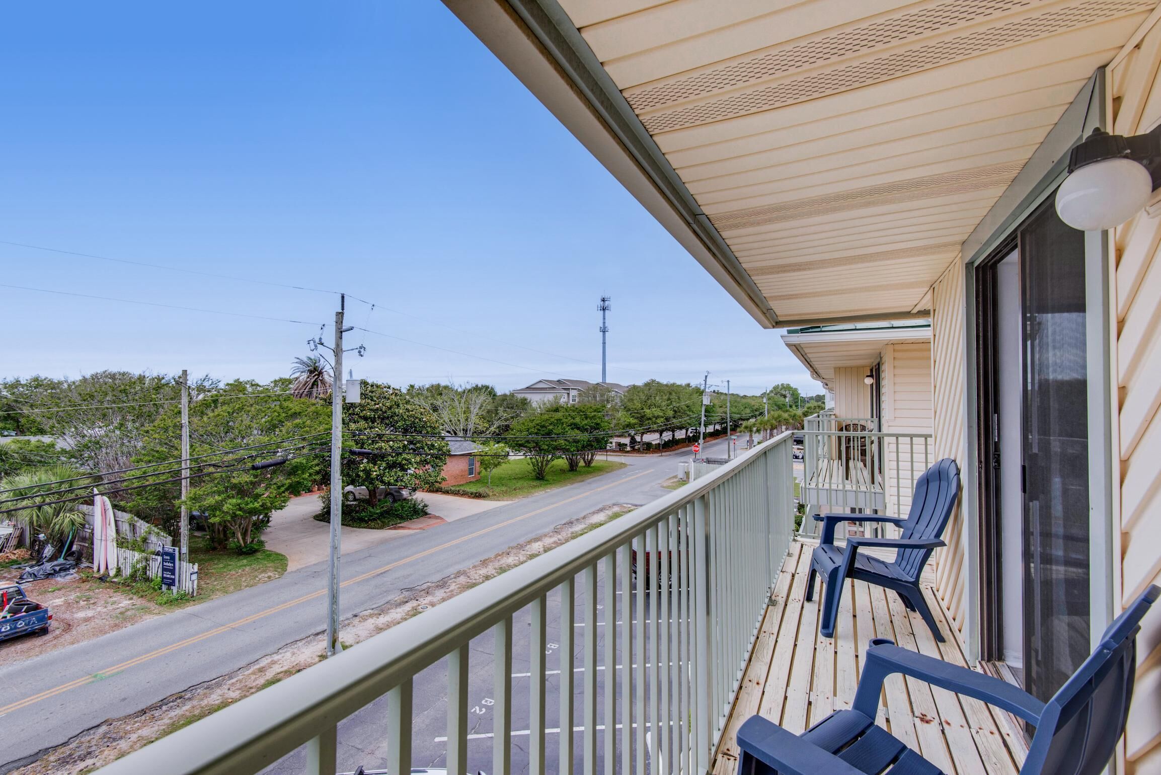 A balcony with a view of a road and surrounding greenery.
