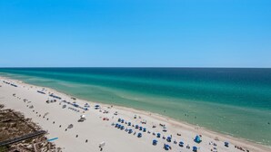 A beach with rows of blue umbrellas and beach chairs, a clear sky, and calm sea. - Majestic Beach Towers 1-1302 (Panama City Beach)