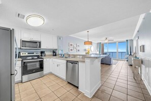 A modern kitchen with white cabinets, stainless steel appliances, and a large island with a sink. - Majestic Beach Towers 1-1302 (Panama City Beach)