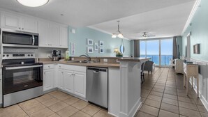 A modern kitchen with white cabinets, stainless steel appliances, and a large island. - Majestic Beach Towers 1-1302 (Panama City Beach)