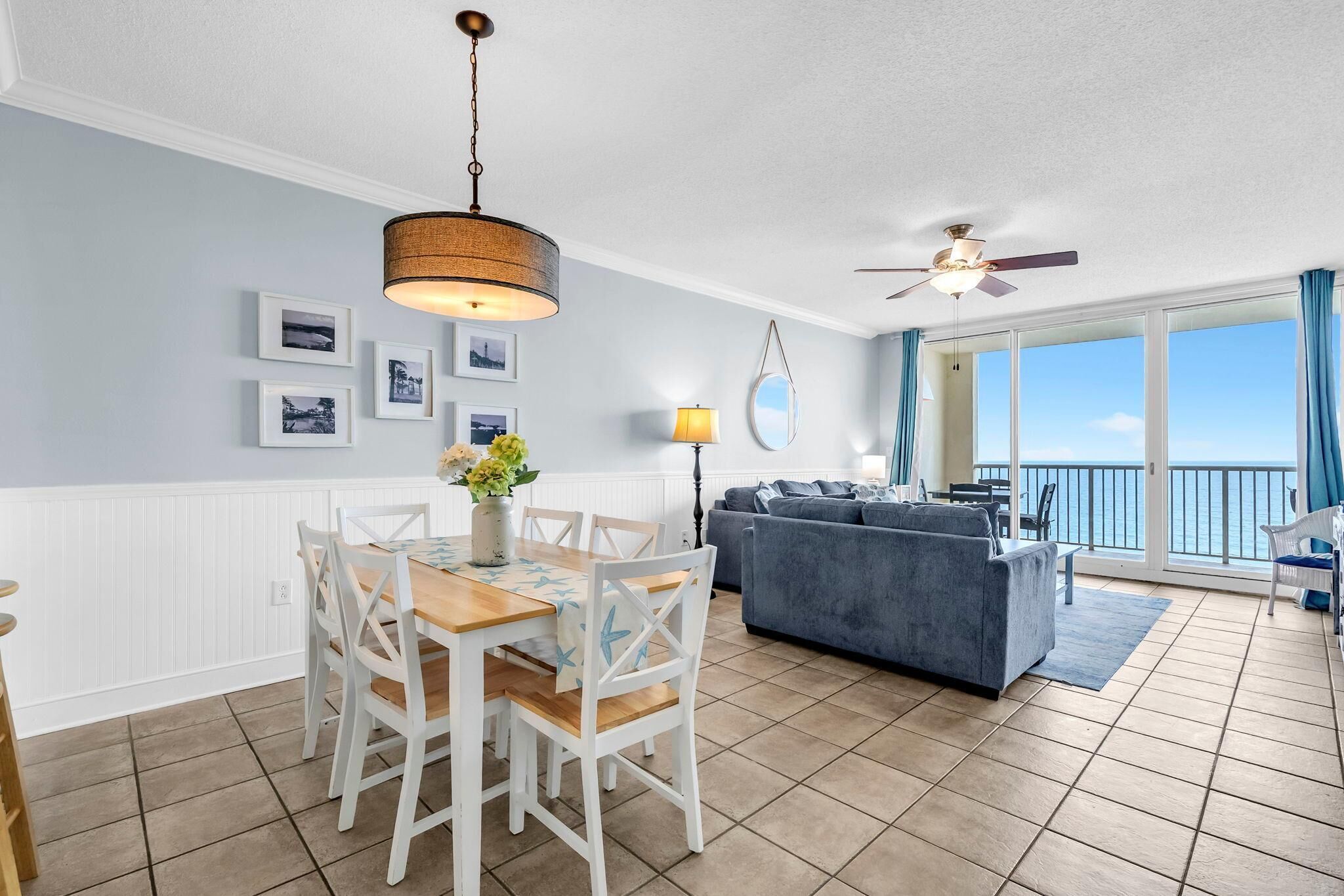 A spacious living area with a dining table, chairs, a sofa, and a balcony with a view.