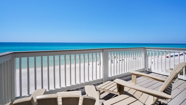 Una terraza de madera con sillones de descanso con vista a la playa.