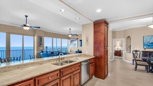 A spacious kitchen with a large island, wooden cabinets, and a view of the ocean. - Hidden Dunes 1803 (Panama City Beach)