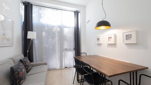 Un salon moderne avec un canapé, une table à manger en bois et des chaises noires.