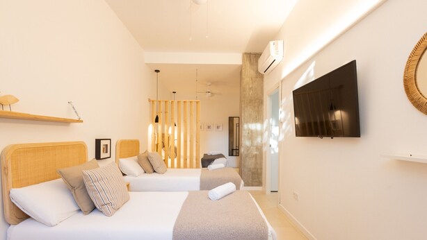 Une chambre d’hôtel moderne équipée de deux lits, d’un téléviseur à écran plat et d’un ventilateur de plafond.