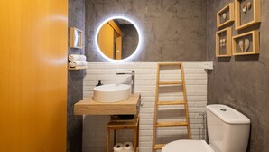 Une salle de bain moderne avec un grand miroir rond, un meuble-lavabo en bois, des toilettes et une échelle en bois.