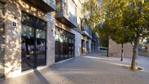 Un bâtiment avec une enseigne en forme de « B », de grandes fenêtres et un arbre devant.