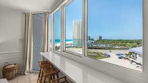 A balcony with wicker furniture, a view of the beach, and a cityscape in the distance. - Top of the Gulf 808- Gulf Coast Getaway (Panama City Beach)