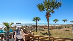 A wooden deck leading to beach chairs and a palm tree, overlooking the ocean. - Top of the Gulf 808- Gulf Coast Getaway (Panama City Beach)