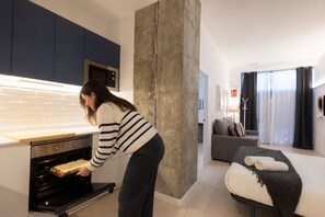 Une femme se trouve dans une cuisine au design moderne, équipée d’un grand four et d’un four à micro-ondes.
