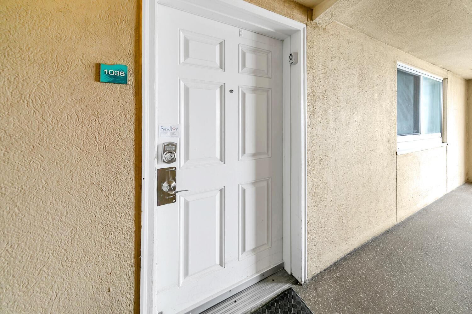 A white door with a keypad lock and a small sign above it.