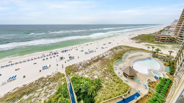 A beach resort with a pool area, beach chairs, and a view of the ocean. - Emerald Beach 1036 - Turquoise Turtle (Panama City Beach)