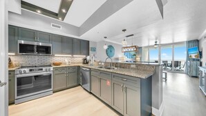 A modern kitchen with grey cabinets, stainless steel appliances, and a large island. - Emerald Beach 1036 - Turquoise Turtle (Panama City Beach)