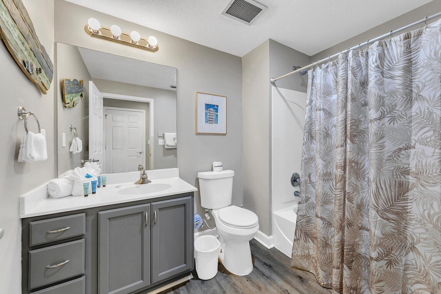 A bathroom with a vanity, sink, mirror, toilet, and shower curtain.