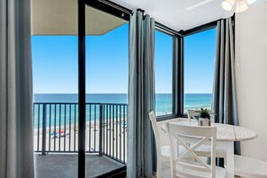 A balcony with a view of the beach, a table with chairs, and a ceiling fan. - Sunbird 709w Beach Life (Panama City Beach)