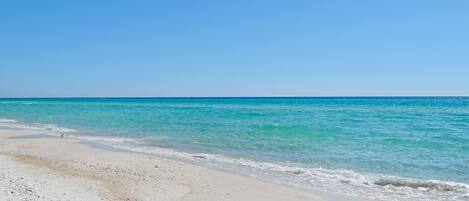 Ein Strand mit klarem türkisblauem Wasser und weißem Sand.