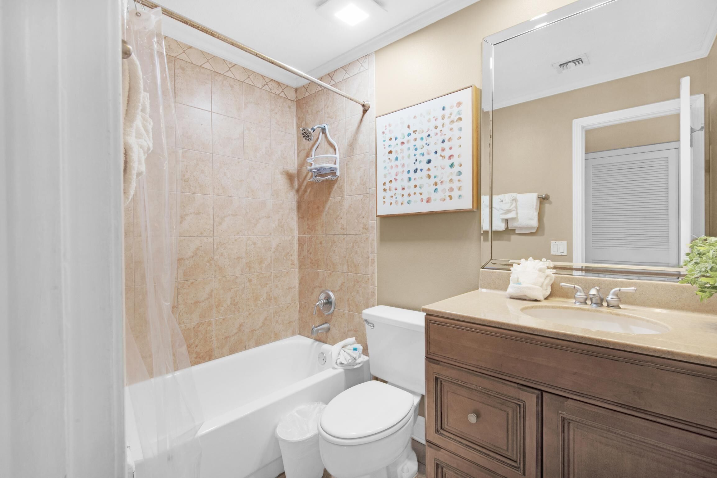 A bathroom with a bathtub, toilet, vanity, and a large mirror.