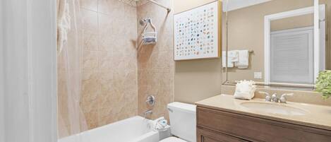 A bathroom with a bathtub, toilet, vanity, and a large mirror.
