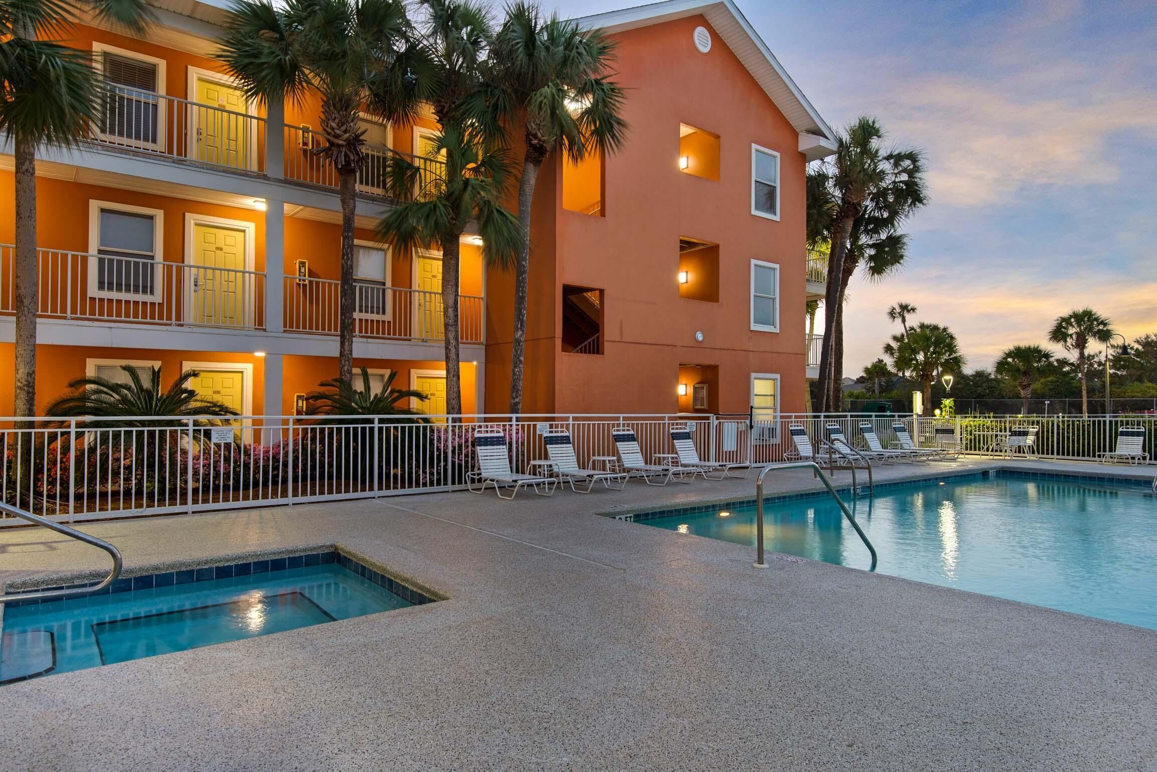 A hotel with a pool, multiple balconies, and palm trees.
