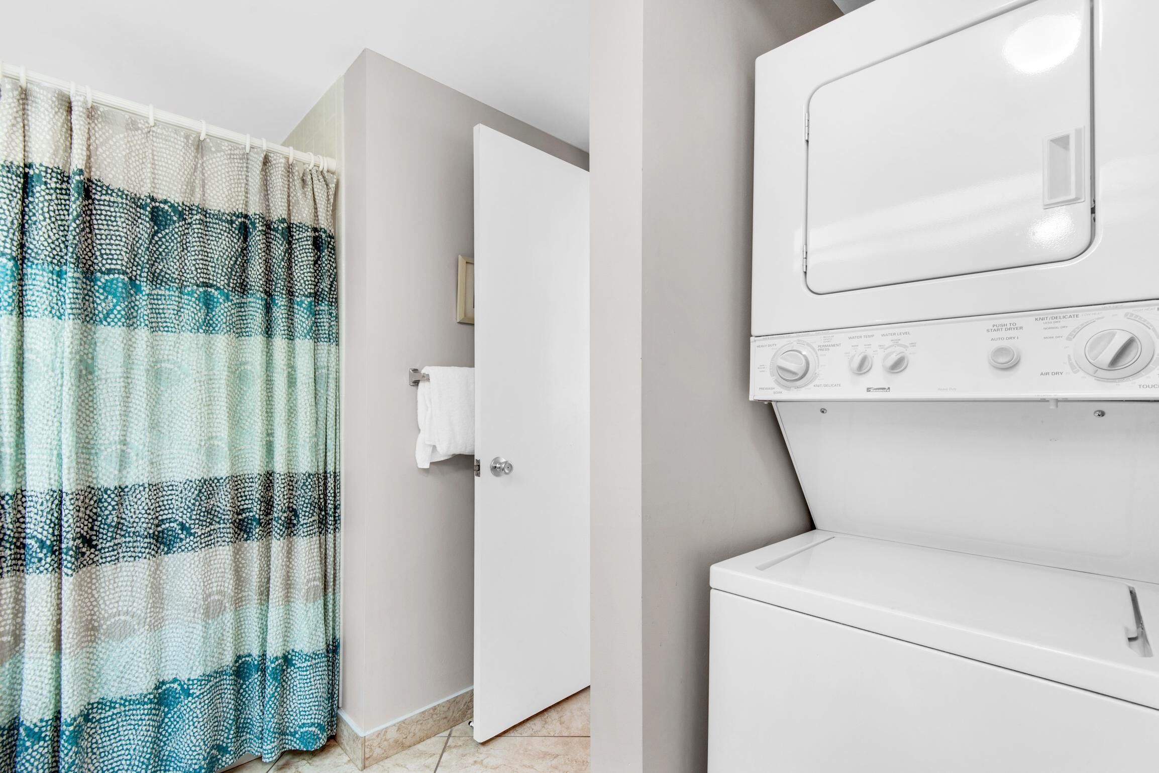 A laundry area with a washing machine and a door with a towel hanging on it.