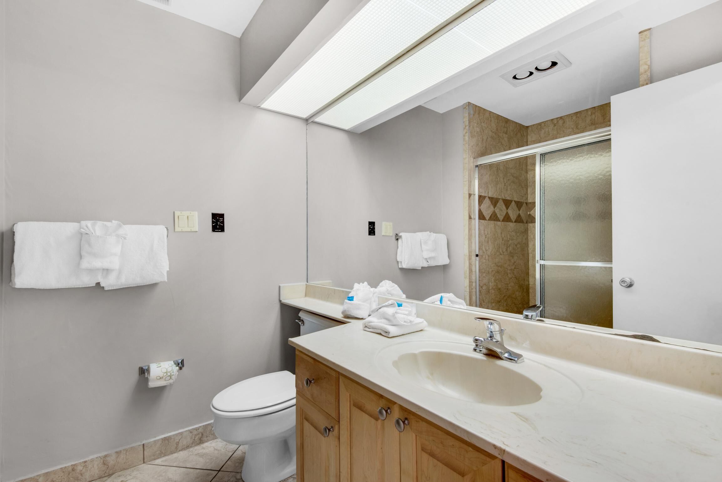 Een moderne badkamer met toilet, wastafel en spiegel.