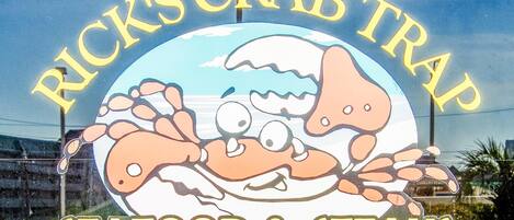 Placa para o Rick's Crab Trap, destacando frutos do mar e bifes.