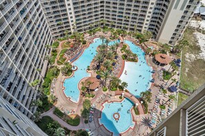 A high-rise hotel with multiple swimming pools, lush landscaping, and a beach area. - Shores of Panama 1802 (Panama City Beach)