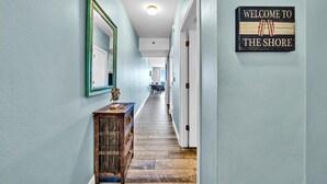 A hallway with a wooden console table, a mirror, and a welcome sign.