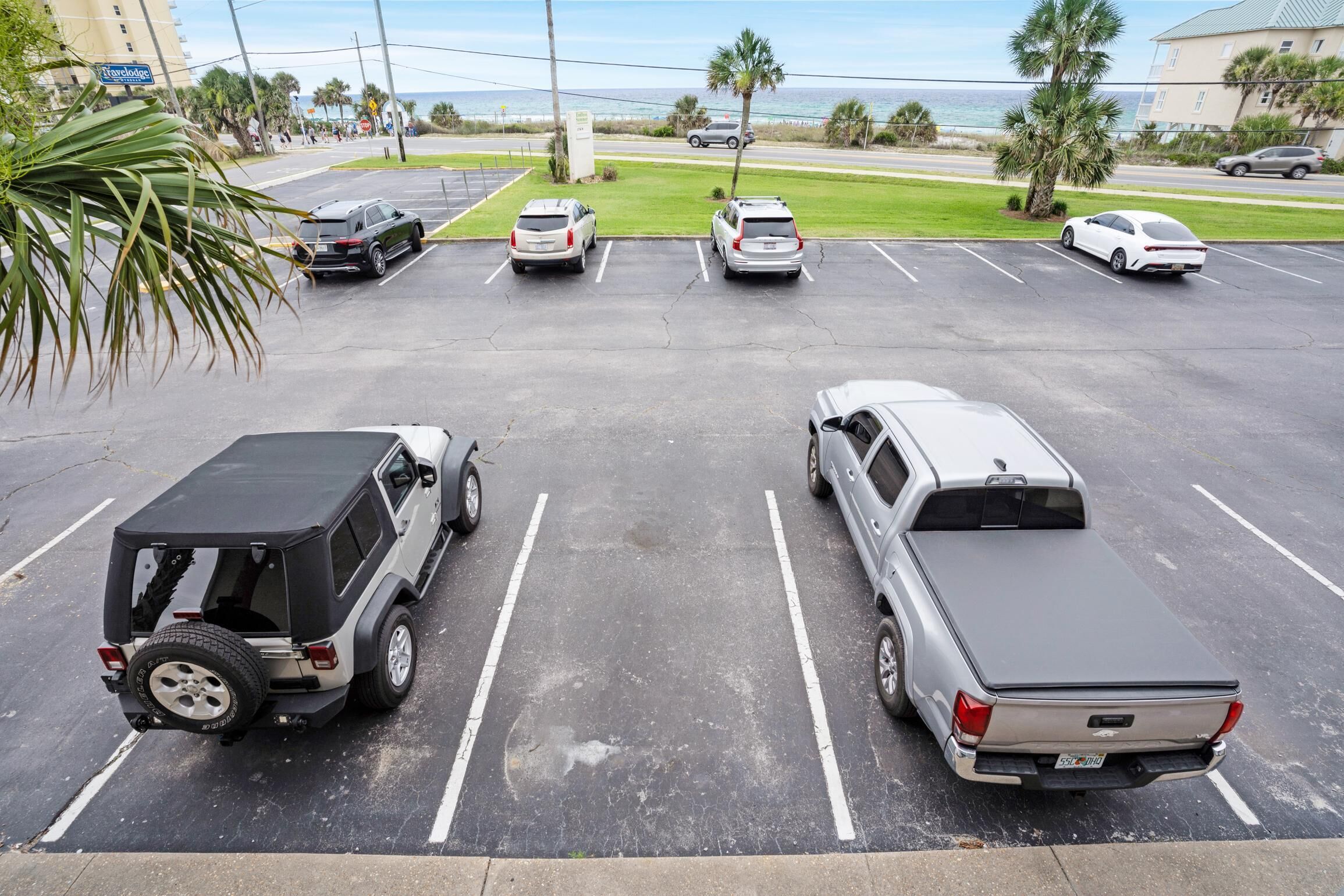A parking lot with several cars, including a black SUV and a silver pickup truck.
