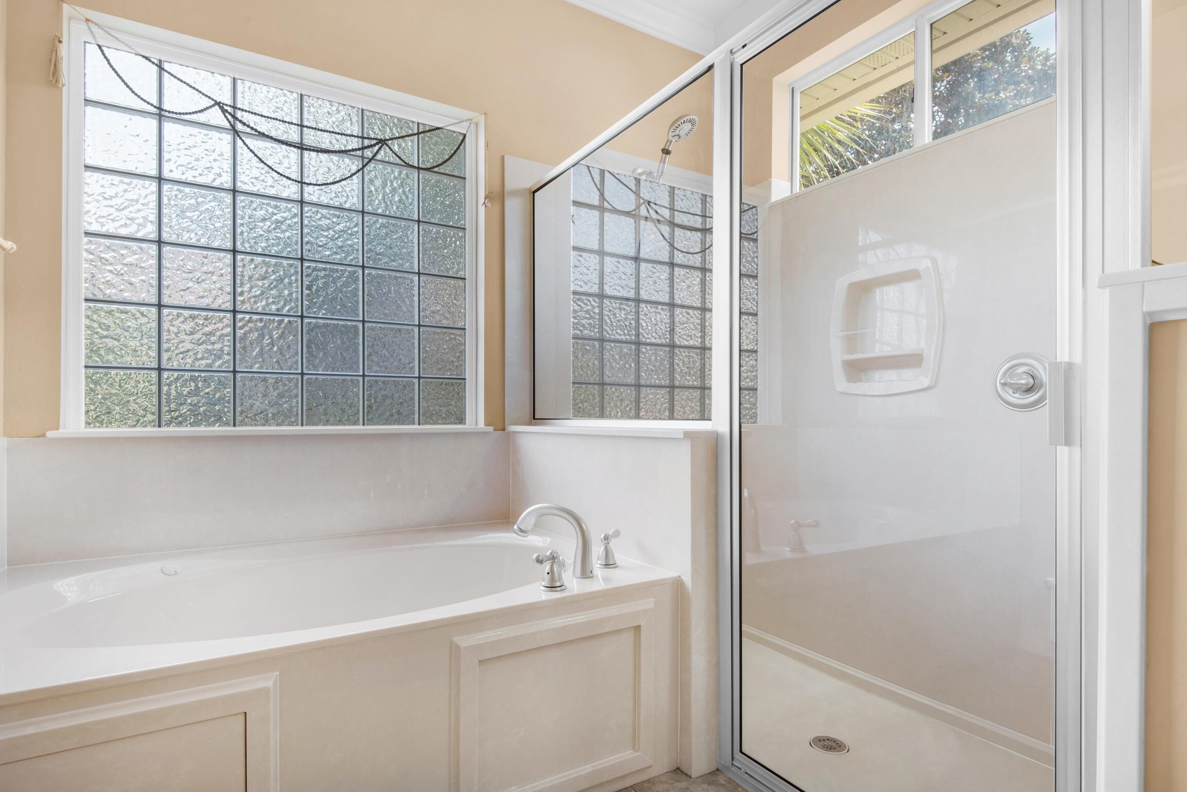 A bathroom with a bathtub, a shower, and a window with frosted glass.
