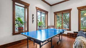 A ping pong table in a room with large windows, wooden floors, and potted plants. - Cozy Guest House on Fitzhugh Rd in the Hill Country, 14 miles to downtown Austin (Austin)
