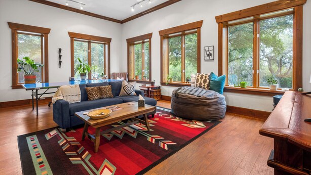 A spacious living room with a blue sofa, a wooden coffee table, and a large window with a view of trees. - Cozy Guest House on Fitzhugh Rd in the Hill Country, 14 miles to downtown Austin (Austin)