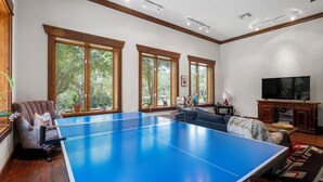 A spacious living room with a ping pong table, large windows, a comfortable seating area, and a television. - Cozy Guest House on Fitzhugh Rd in the Hill Country, 14 miles to downtown Austin (Austin)