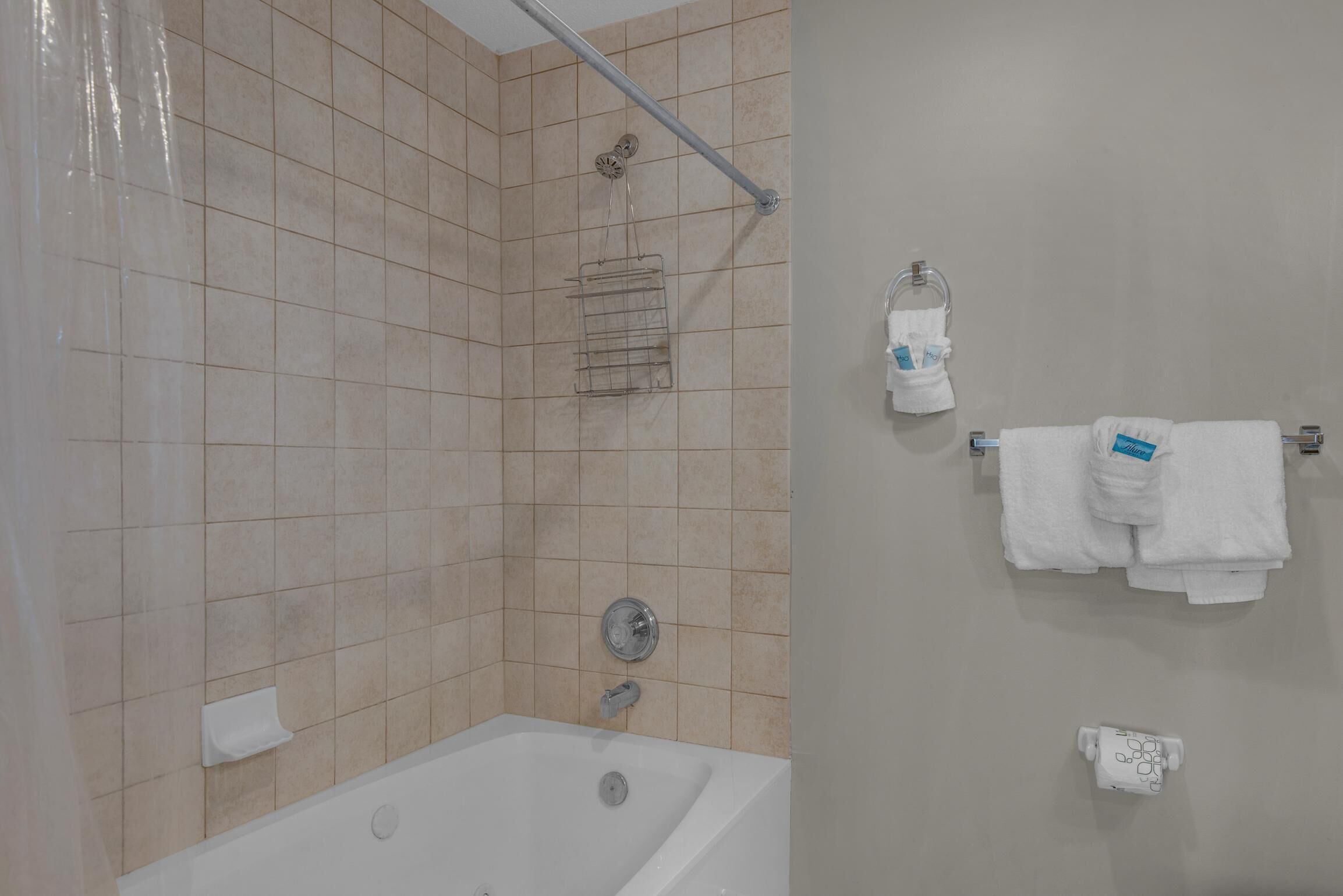 A bathroom with a bathtub, a shower area, and a towel rack with towels.