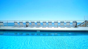 A swimming pool with lounge chairs and a metal railing. - Leeward Key 1201 (Miramar Beach)