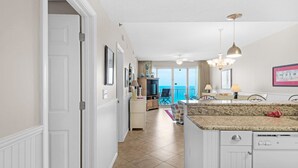 A spacious kitchen with a granite countertop, a dishwasher, and a dining area with a table and chairs. - Leeward Key 904 (Miramar Beach)
