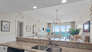 A modern kitchen with granite countertops, stainless steel sink, and white cabinetry. - Leeward Key 904 (Miramar Beach)