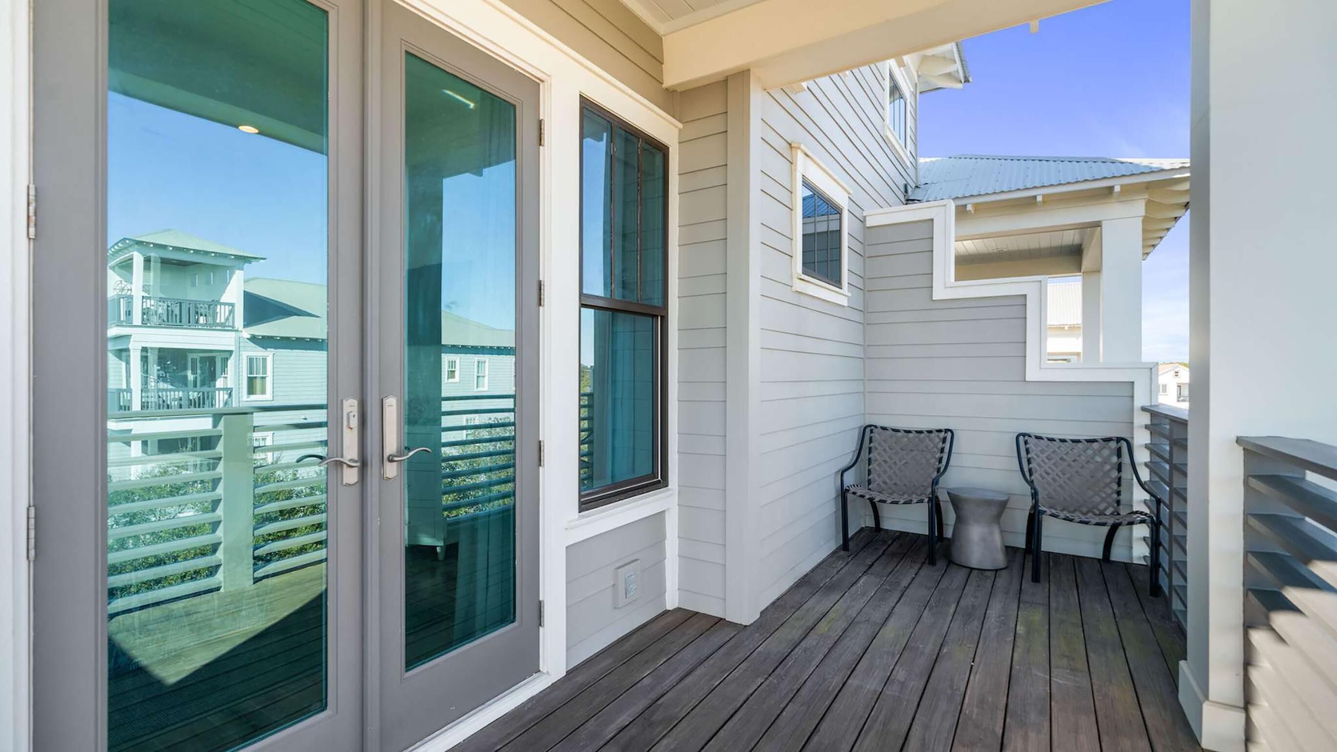 A balcony with a wooden deck, two chairs, and a small table.