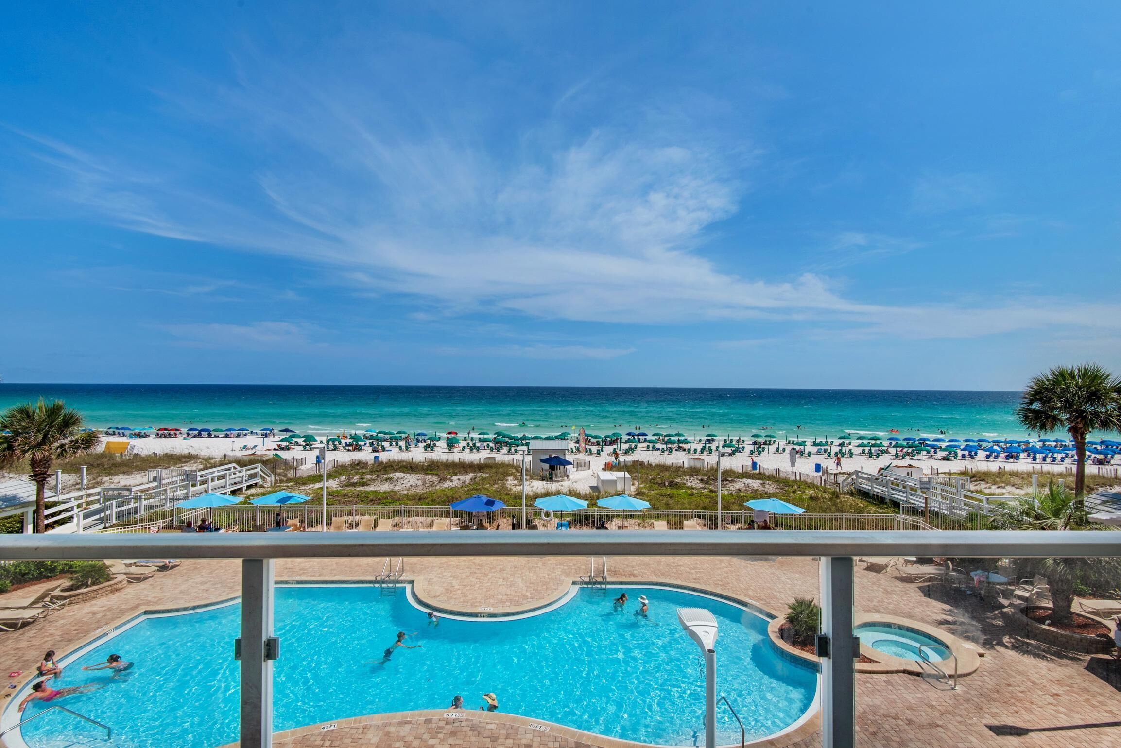 A pool area with a view of the beach and ocean.