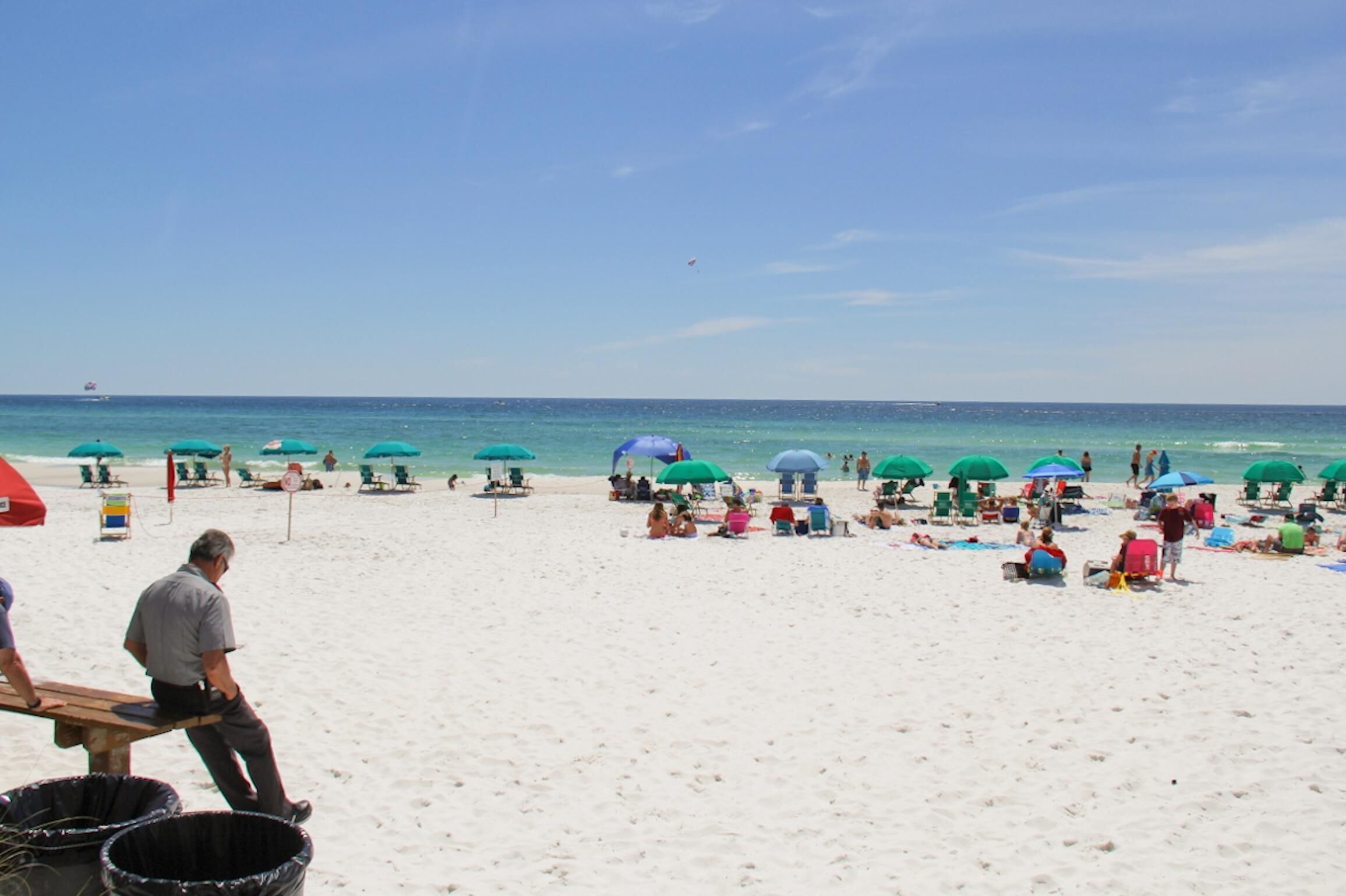 Ein Strand mit vielen Sonnenschirmen und entspannten Menschen.