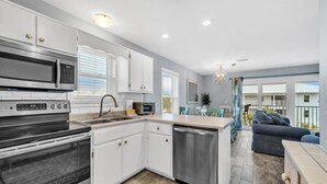 A modern kitchen with white cabinets, stainless steel appliances, and a central island. - Beachside Villas 933 (Santa Rosa Beach)