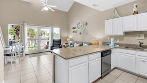 A spacious kitchen with a large island, white cabinetry, and a ceiling fan. - Caribbean Dunes 225 (Destin)