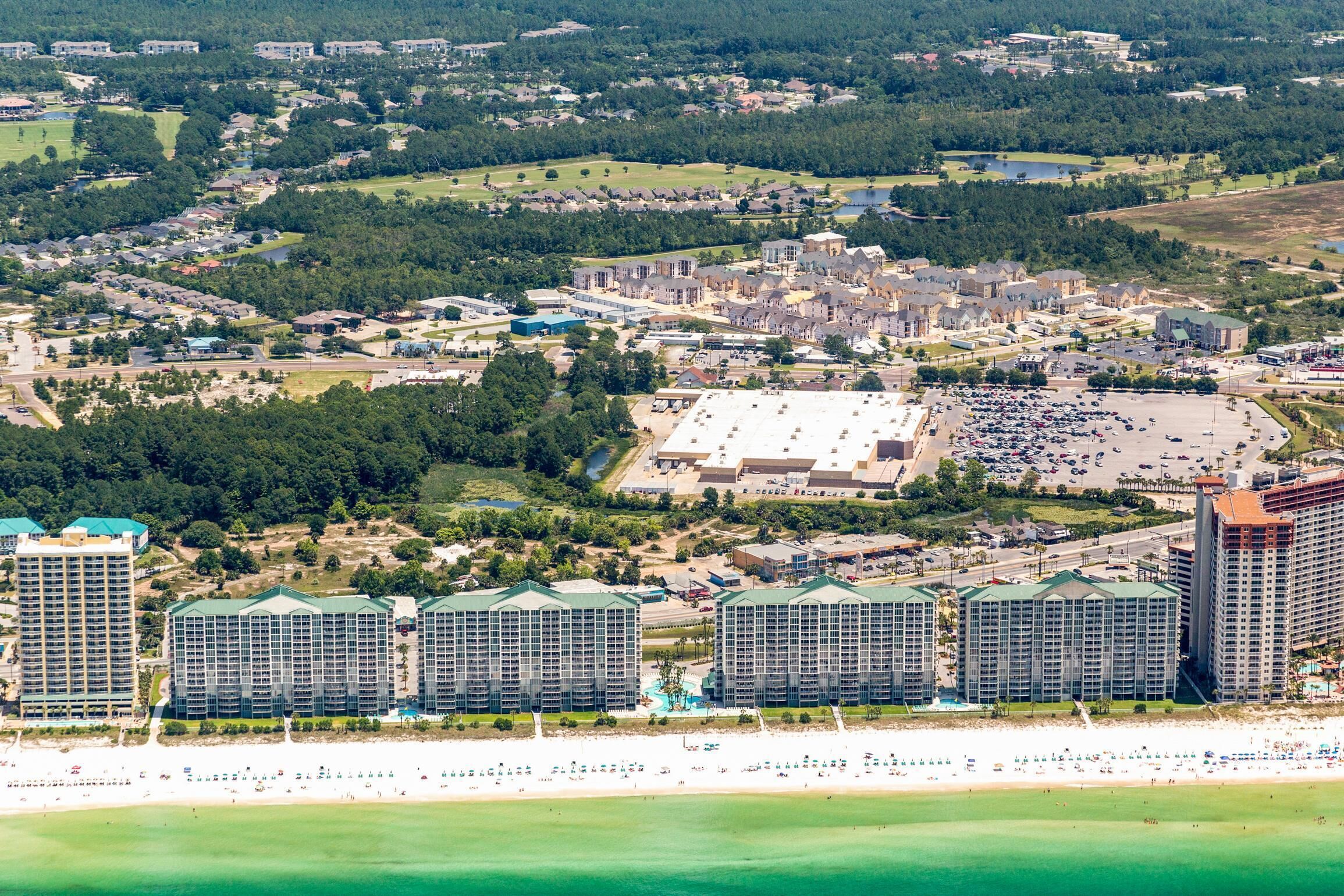 A coastal resort with multiple high-rise buildings, a large parking area, and a beach.